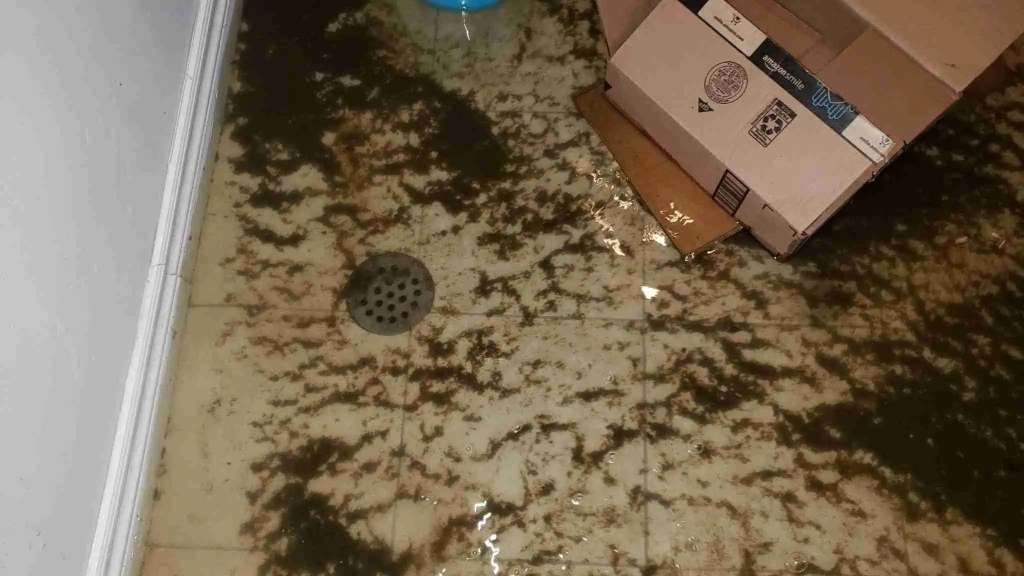 Flooded basement floor with water and mud after a flood event.